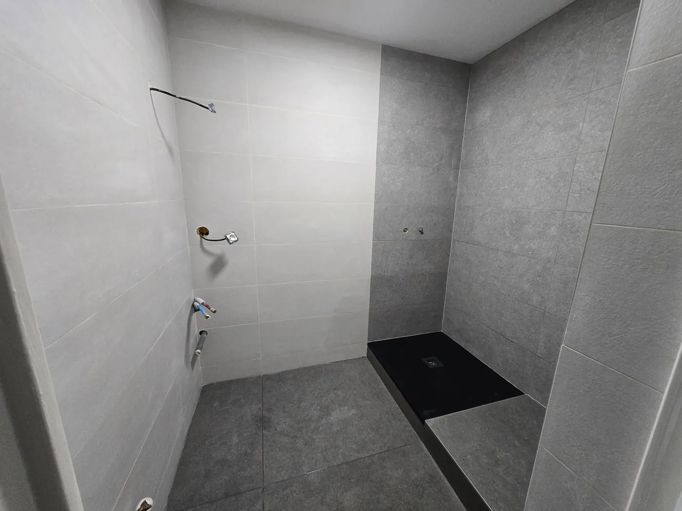 Salle d'eau carrelée gris clair et gris anthracite avec receveur noir