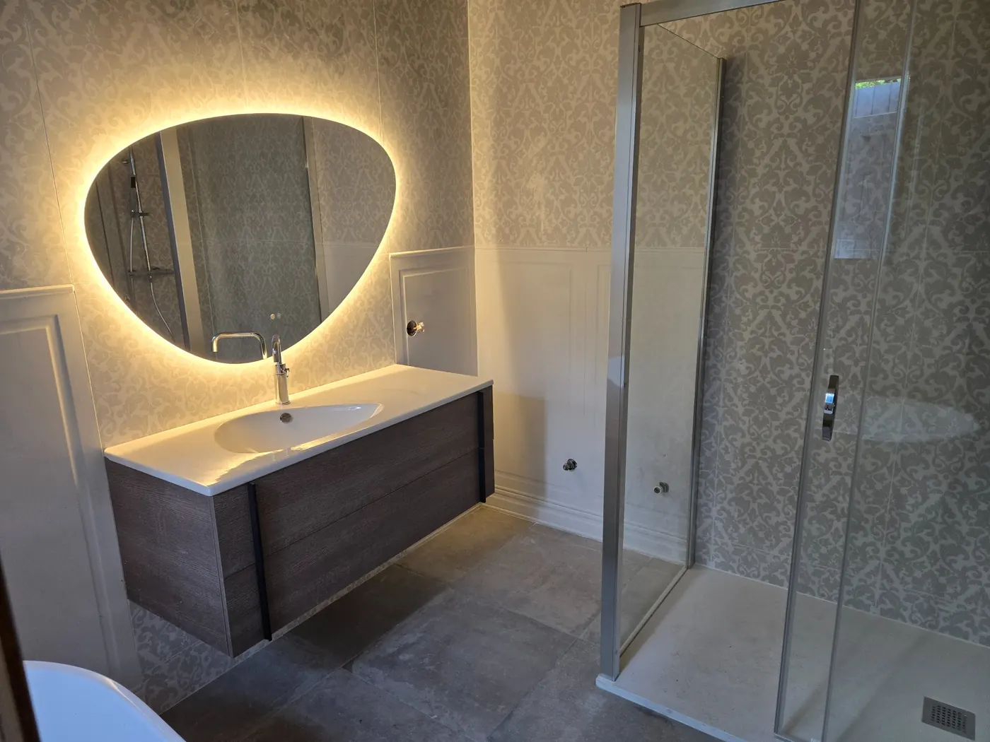 Salle de bains rénovée avec carrelage au sol et habillage mural décoratif